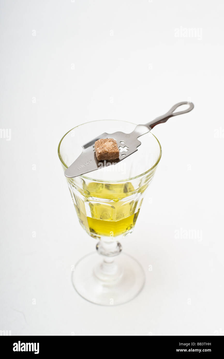 Absinthe glass with a perforated absinthe spoon topped with a piece of raw sugar. Stock Photo