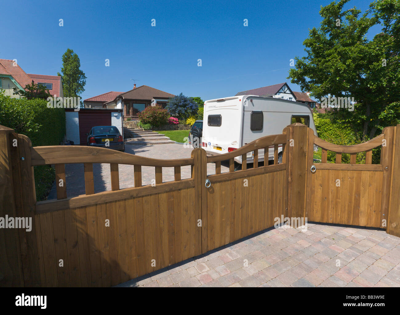 Driveway and garage of detached bungalow with parked cars and caravan Stock Photo