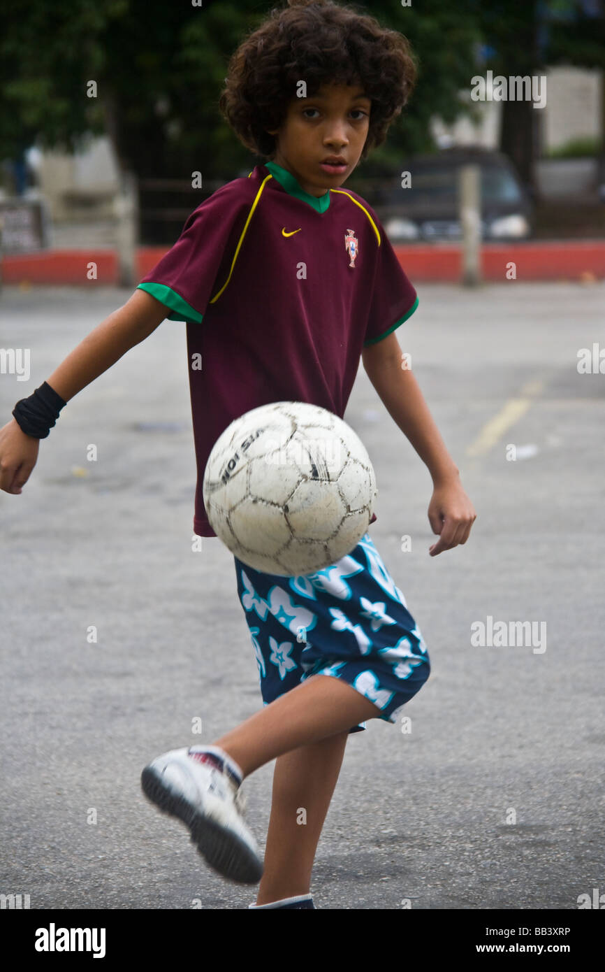 Young brazilian boy playing football on a parking lot in Rio de Janeiro