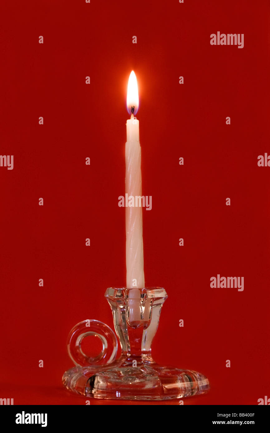 Burning candle in a glass candle holder on red background Stock Photo