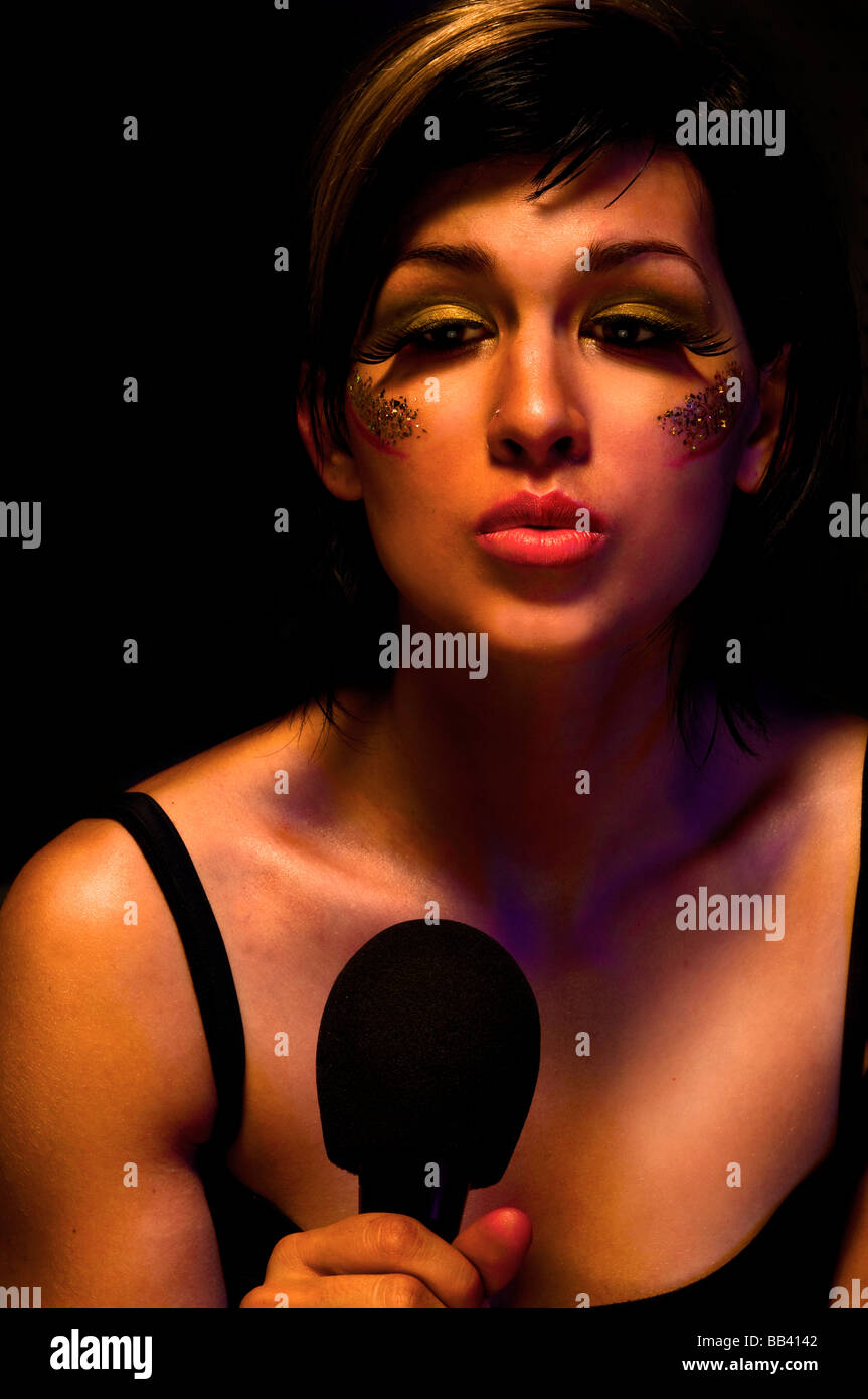 Young Beautiful female. musician, Jazz and Blues singer holding a microphone looks into the
