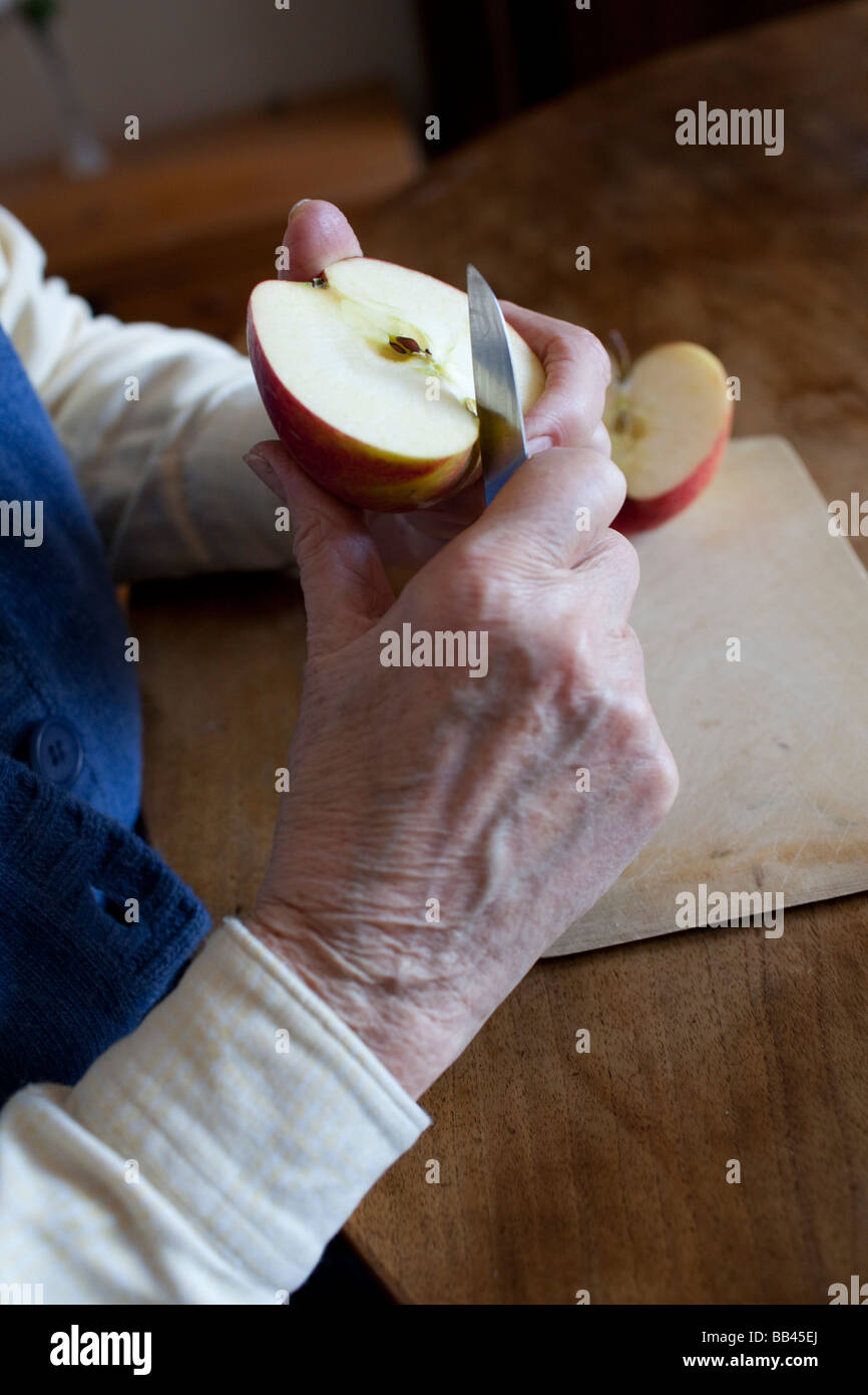 Senior is cutting an apple Stock Photo
