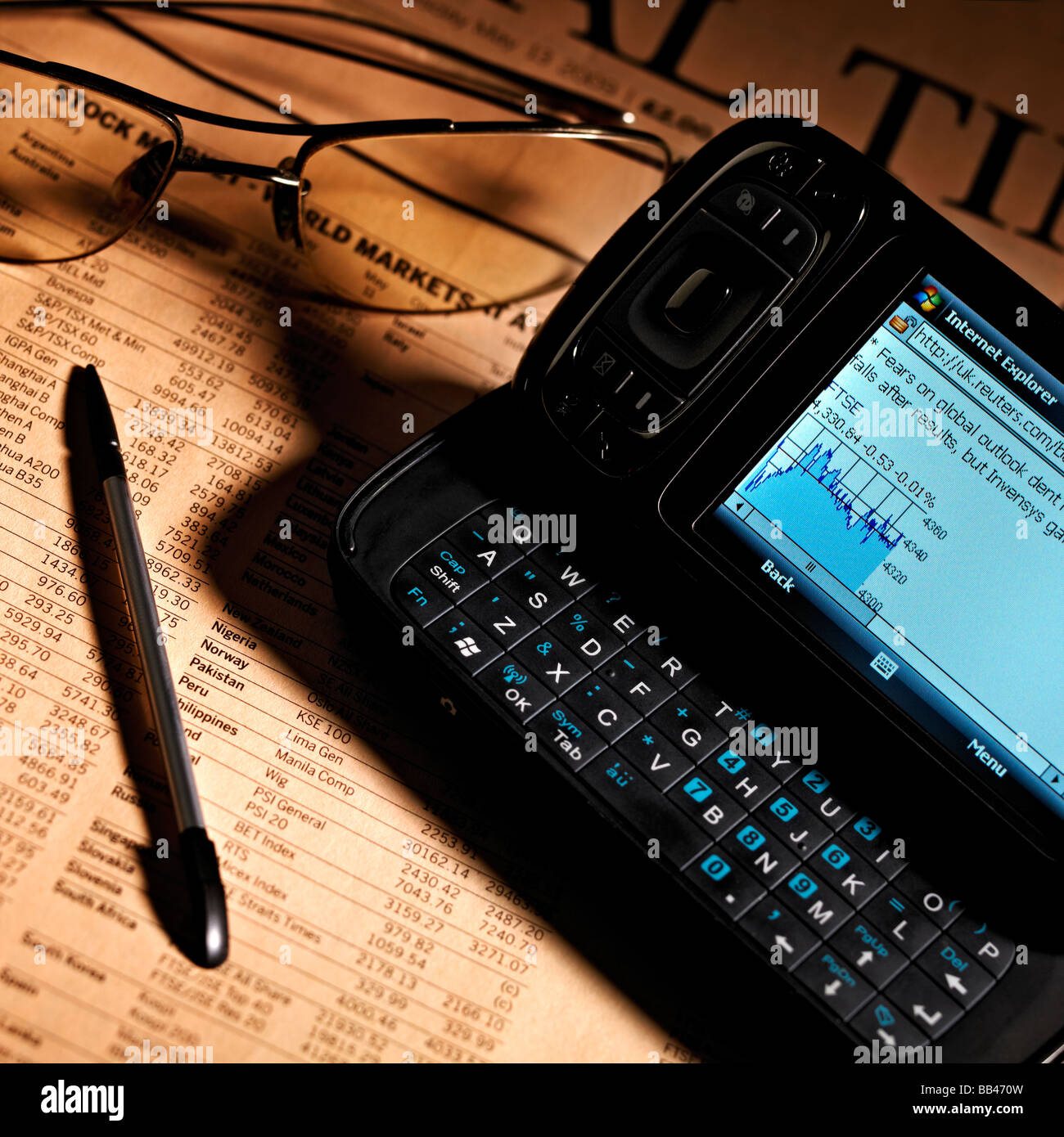 MOBILE PHONE PDA INTERNET ACCESS WITH NEWSPAPER FINANCIAL PAGE Stock Photo