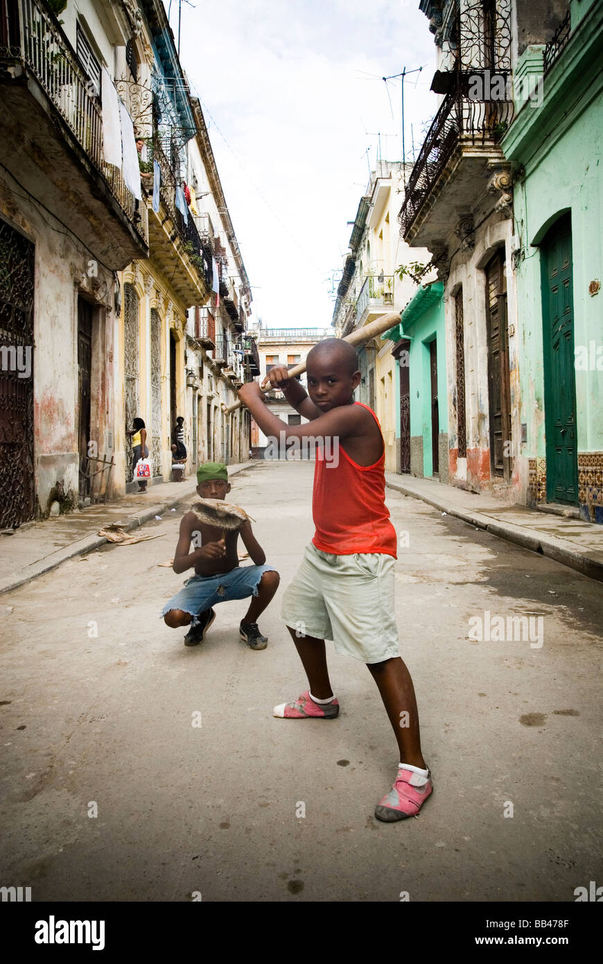 Boy playing baseball in street with broomstick bat, Havana, Cuba. Stock Photo