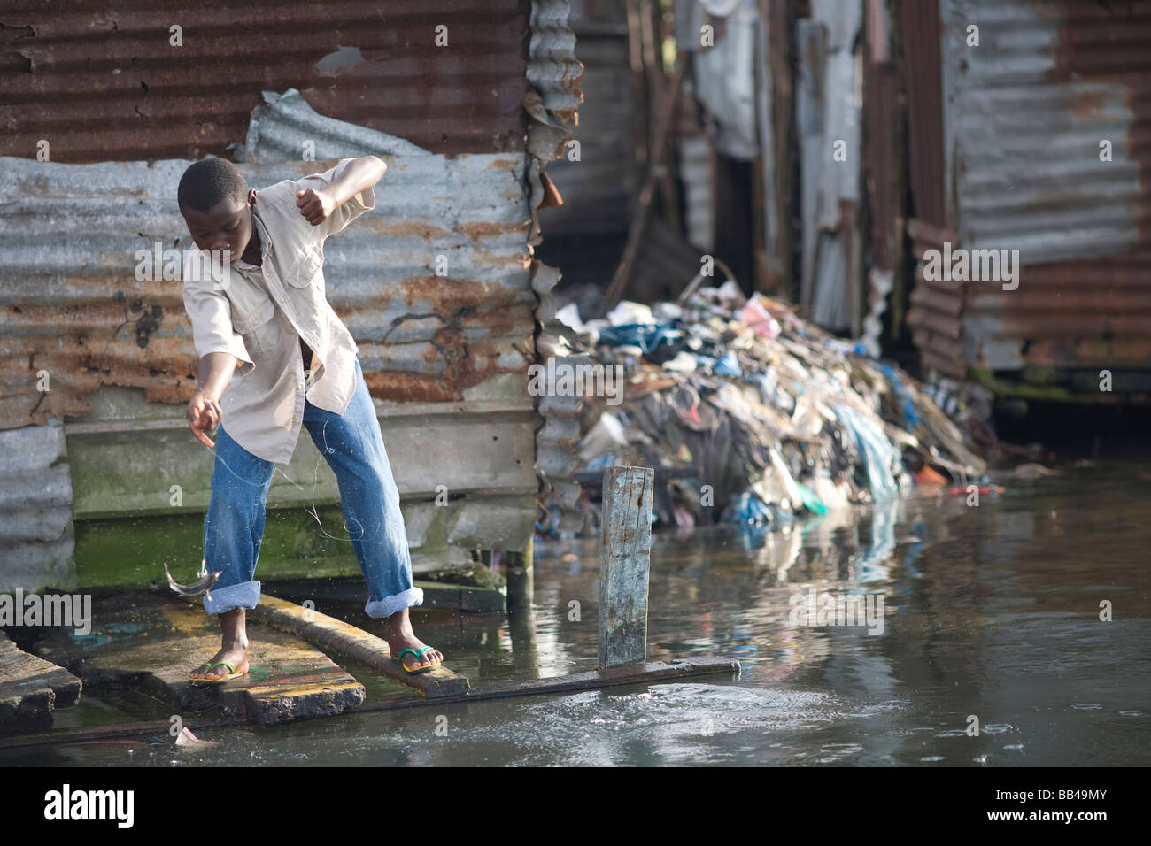 Liberian boy fishing in sewage water in Monrovia, Liberia. Stock Photo
