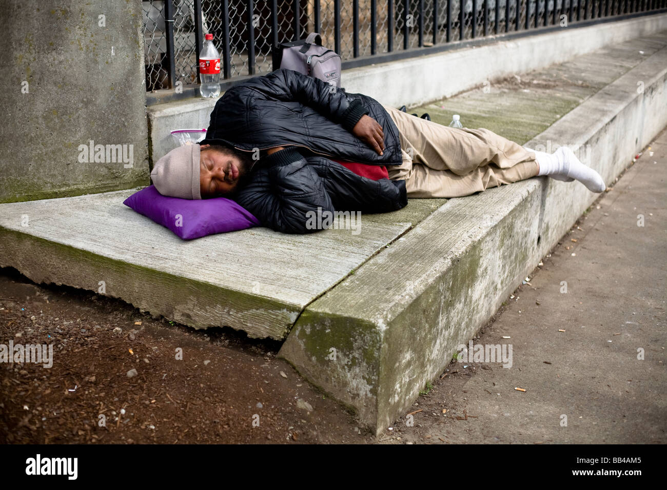 A man sleeps on a concrete sidewalk in Portland, Oregon. Stock Photo
