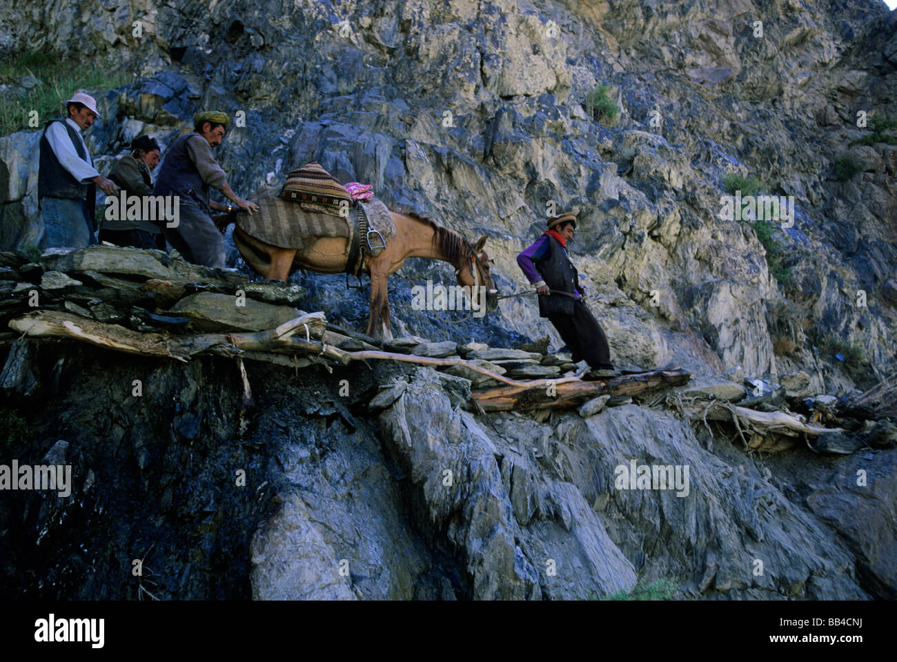 Men guide a horse over a treacherous trail, Wakhan corridor, Sarhad, Afghanistan. Stock Photo