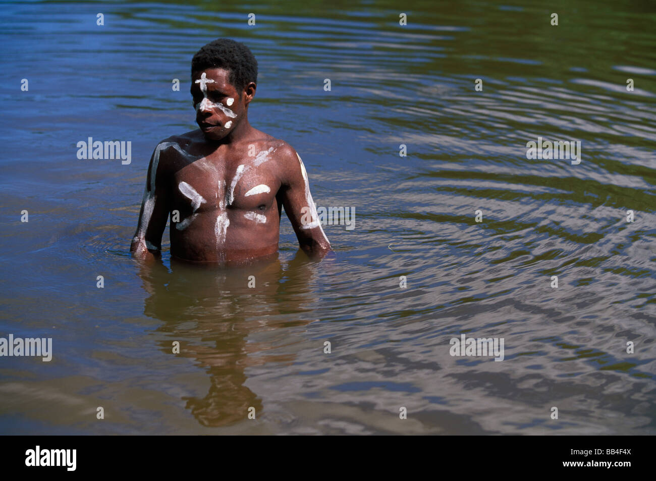 Local native man in white paint standing in the water. Stock Photo