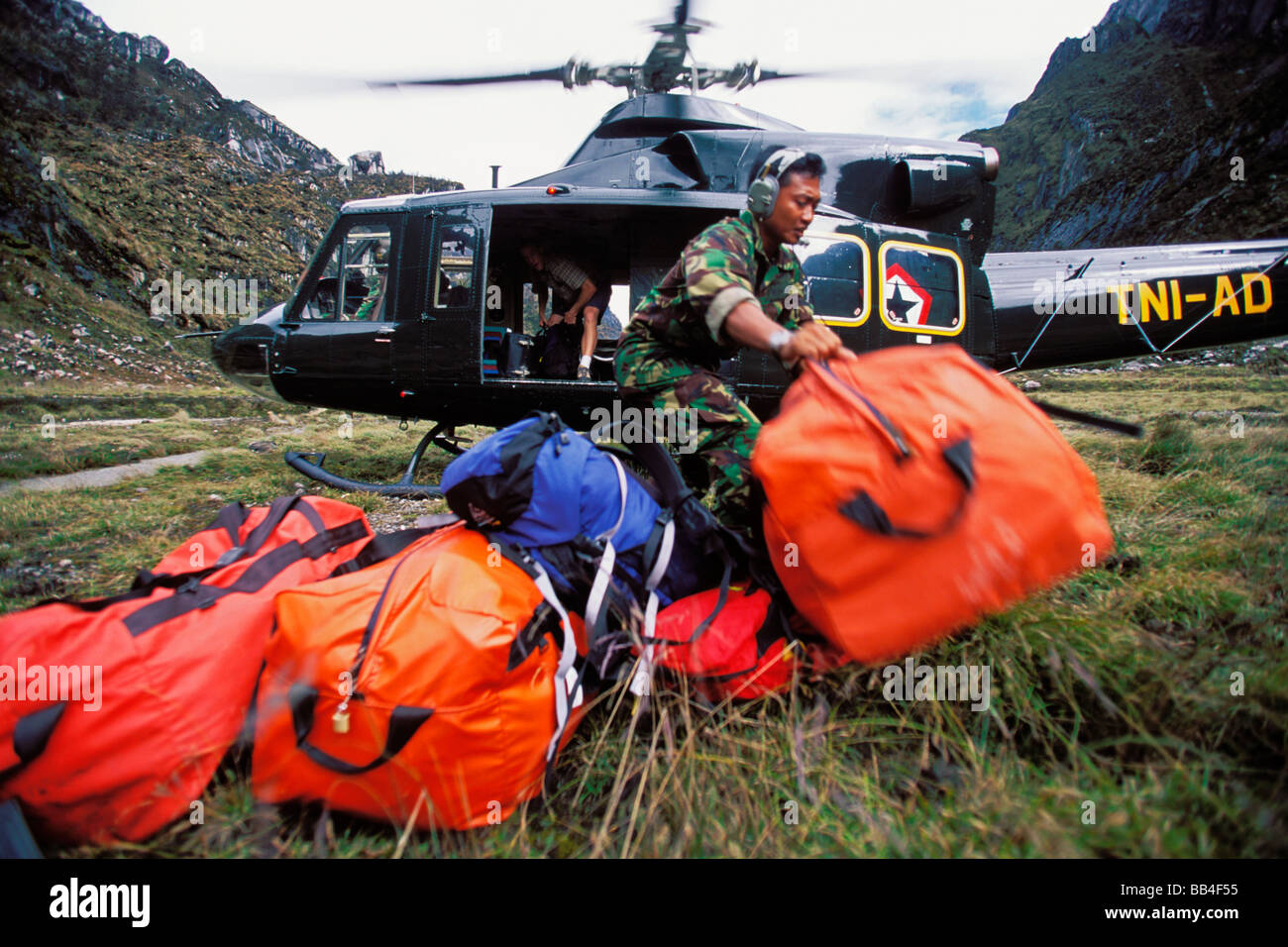 Indonesian military official unloading baggage from a helicopter. Stock Photo