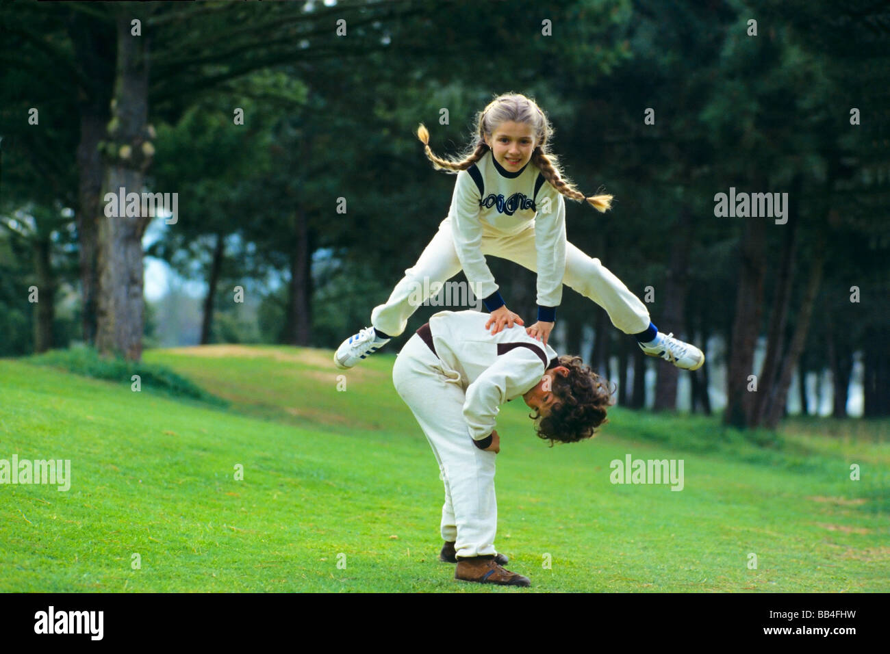 BOY AND GIRL PLAYING LEAPFROG Stock Photo