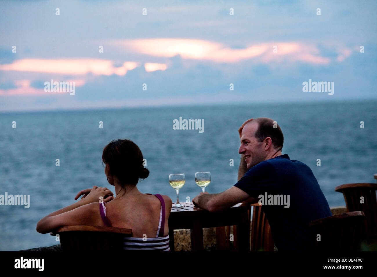 A couple watches the sunset from Cafe de Mar atop the old city wall in Cartagena, Colombia Stock Photo