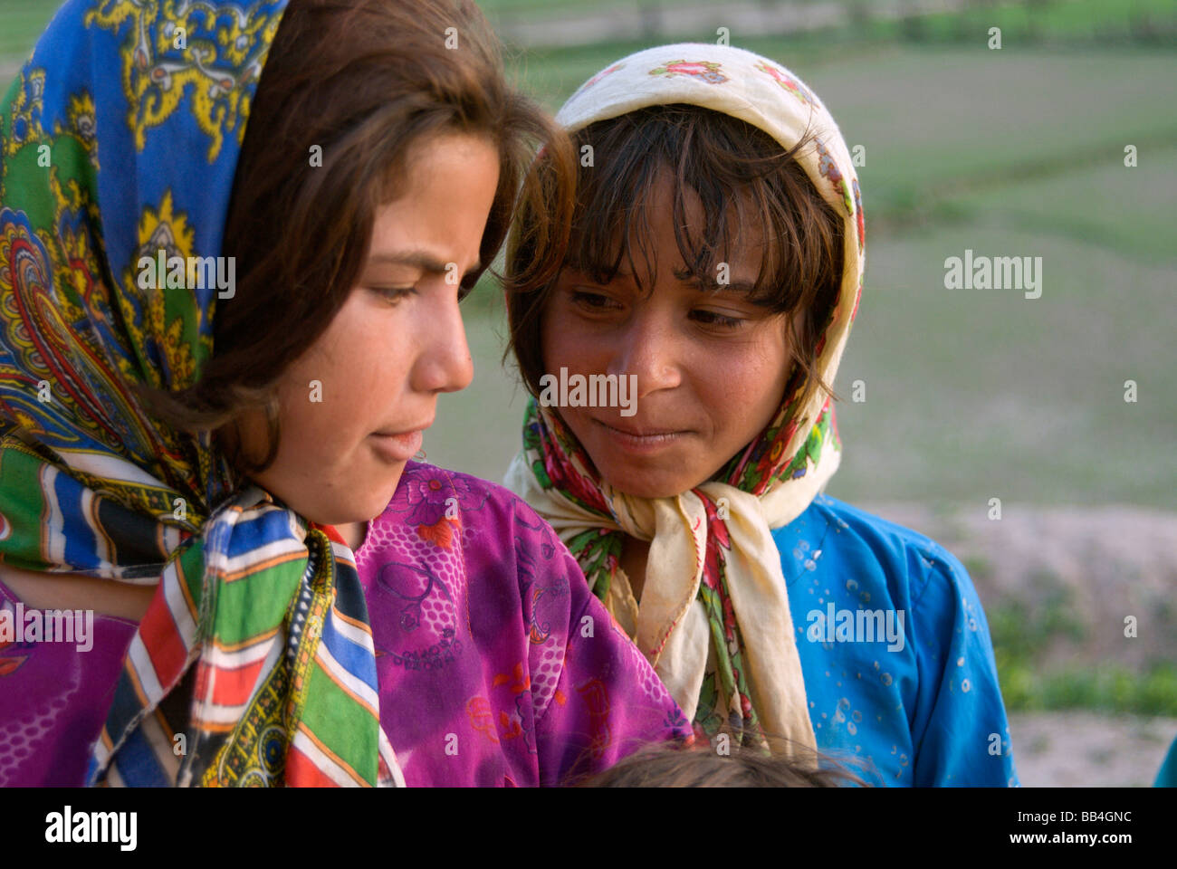 Two young girls share a secret in the Tajik village of Dera Jawal, at the base of the Band-e Baba range,  Herat Province Stock Photo