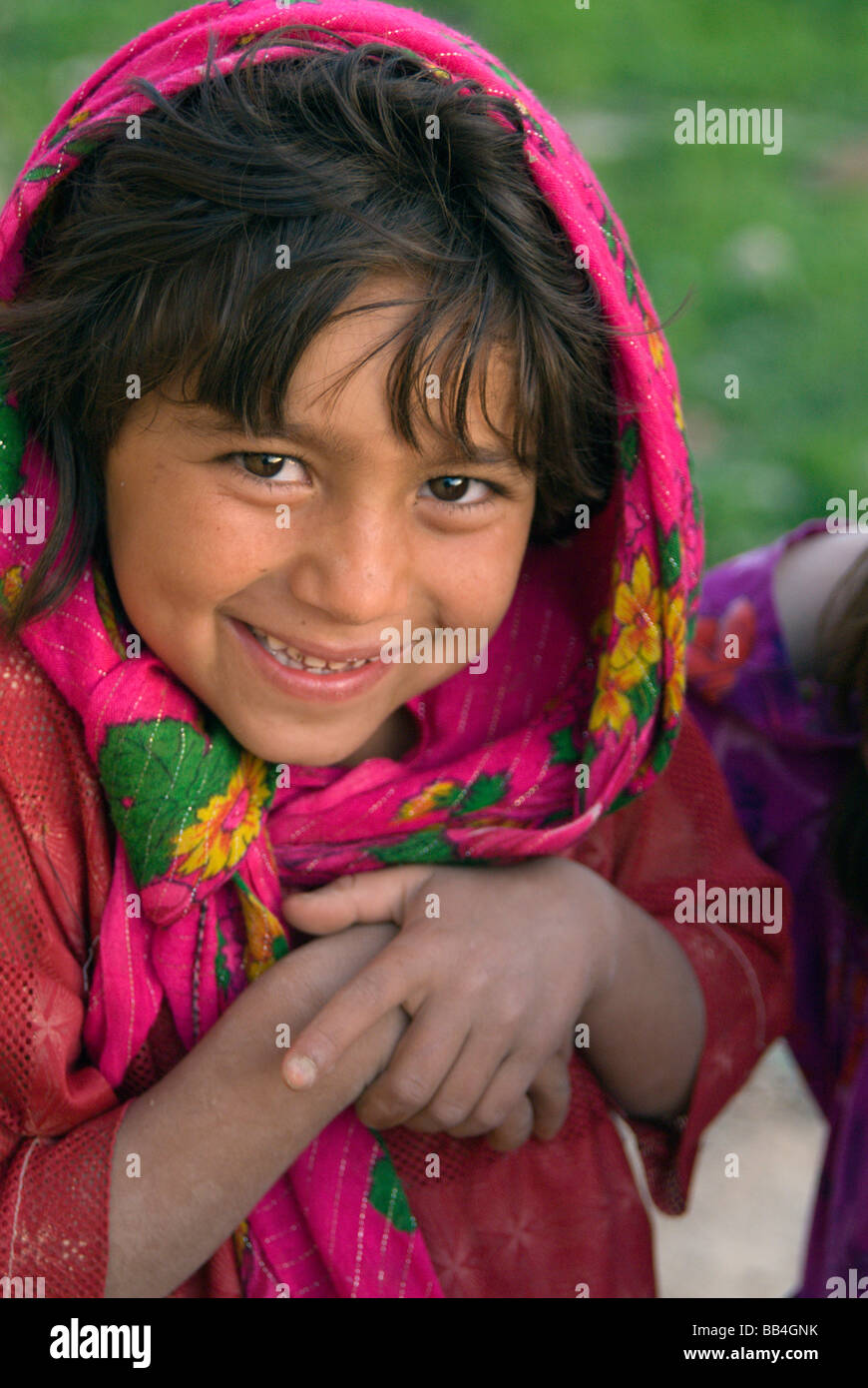 A young girl smiles shyly  in the Tajik village of Dera Jawal, at the base of the Band-e Baba range, Herat Province Stock Photo