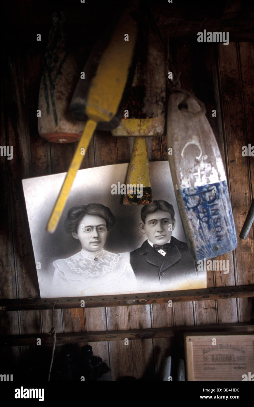 An old photograph and wellused lobster buoys hang in a boat house at