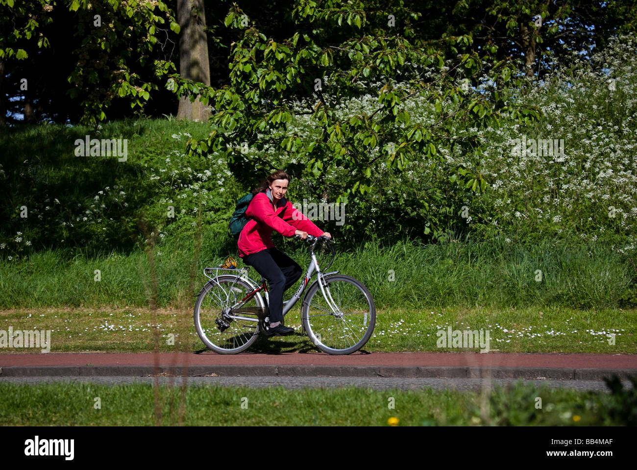 Female cyclist cycling along pavement in Holyrood Park, Edinburgh Scotland, UK, Europe Stock Photo