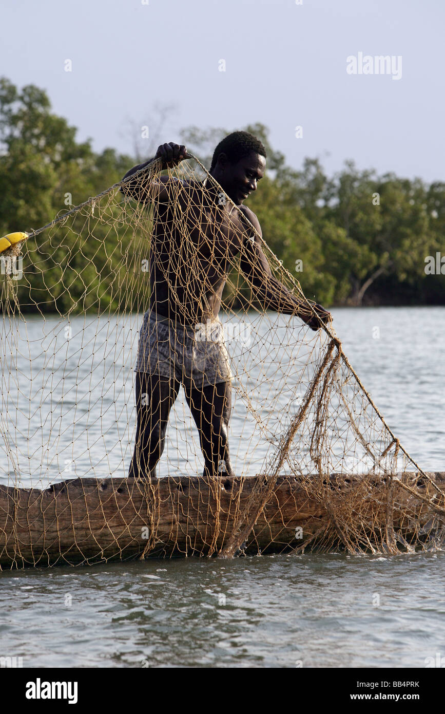 Senegal: Fisherman pulling the net in his dugout canoe on the river Casamance Stock Photo