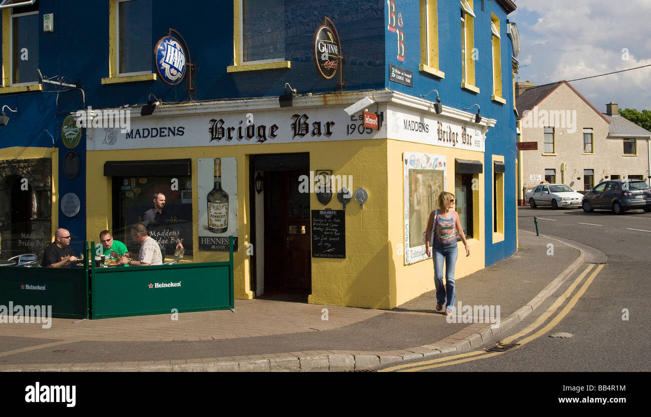 Europe, Ireland, Bundoran. A woman walks past patrons of a pub. Stock Photo