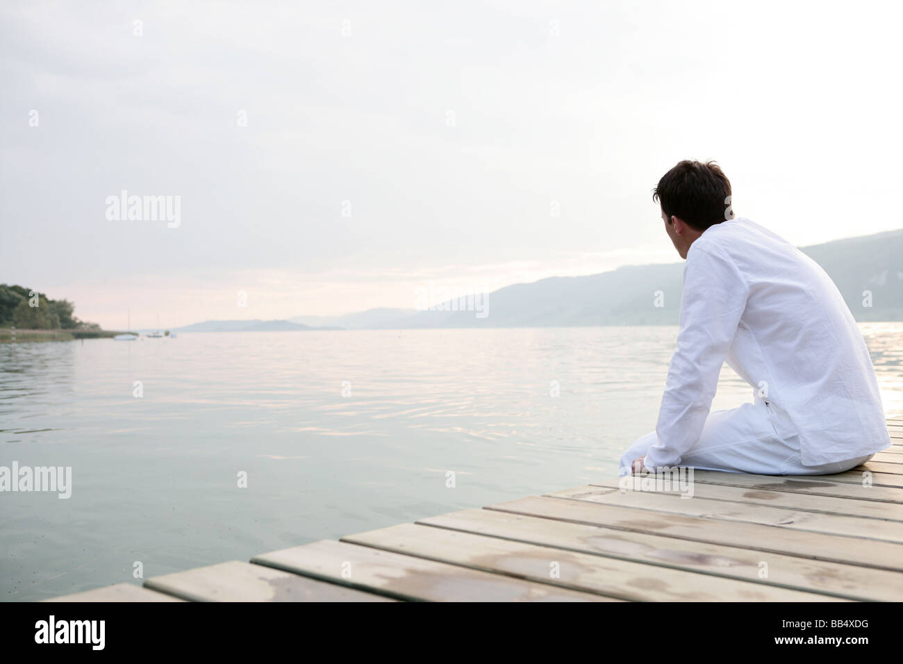 man sitting on a jetty at the lakeside Stock Photo
