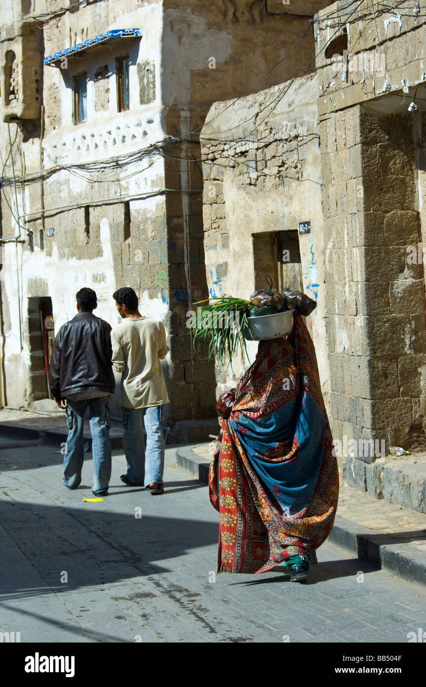 Veiled woman carrying vegetables in the old town district of Sana'a Yemen Stock Photo