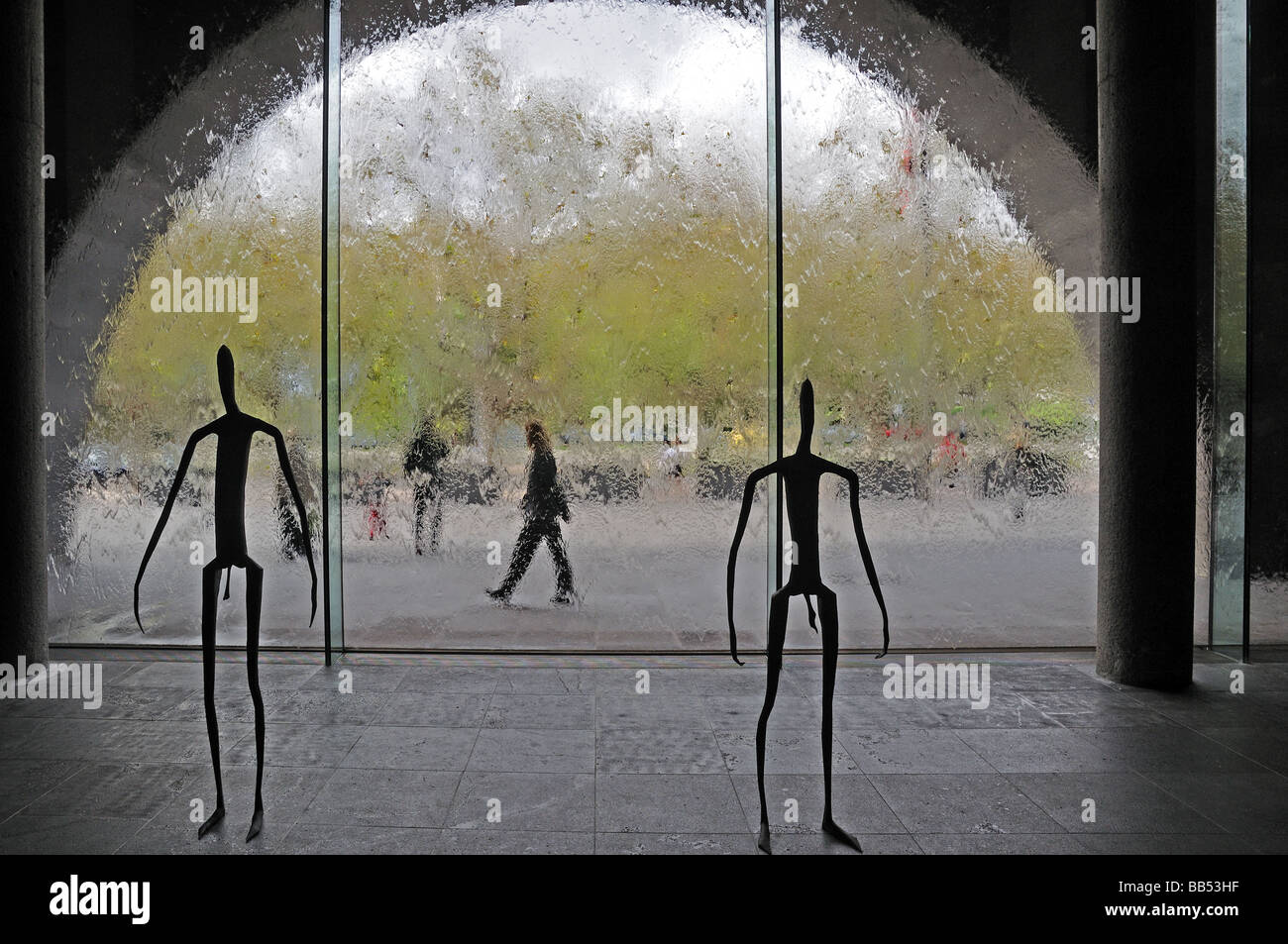 Metal sculpture human stick figures inside Victoria National Gallery Melbourne Australia with glass wall a running water Stock Photo