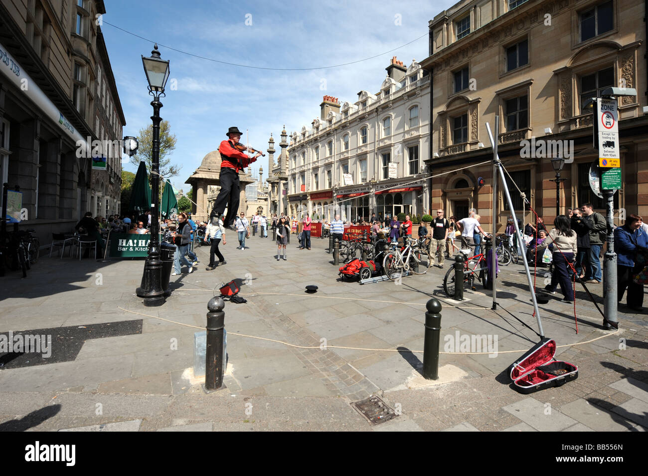 A busker plays a violin while balancing on a tightrope in Brighton city centre Stock Photo