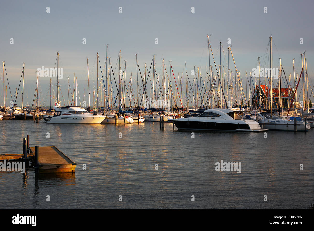 Dutch harbour with sailing boats and landing stage lit by the early evening sun Stock Photo