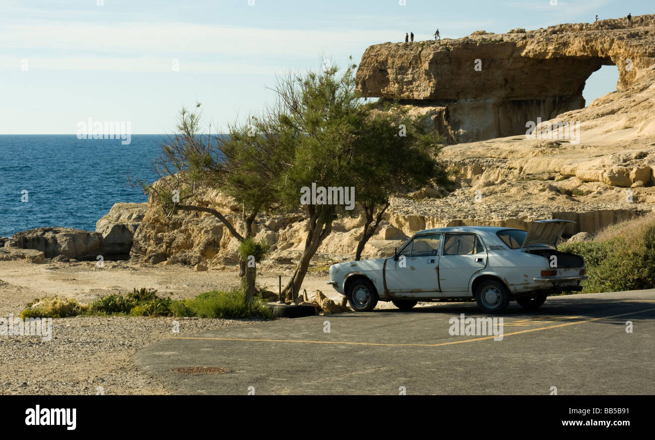 A car parked at Dwejra Point with its boot open in an otherwise empty car park by the Azure Window on the Maltese Island of Gozo Stock Photo