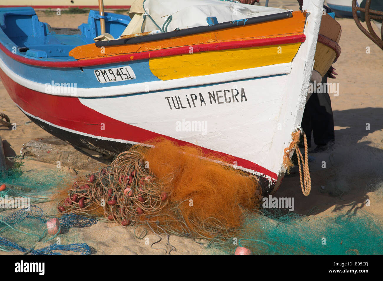 Brightly painted fishing boat in the village of  Olhos D'Agua on the Portuguese Algarve. Stock Photo