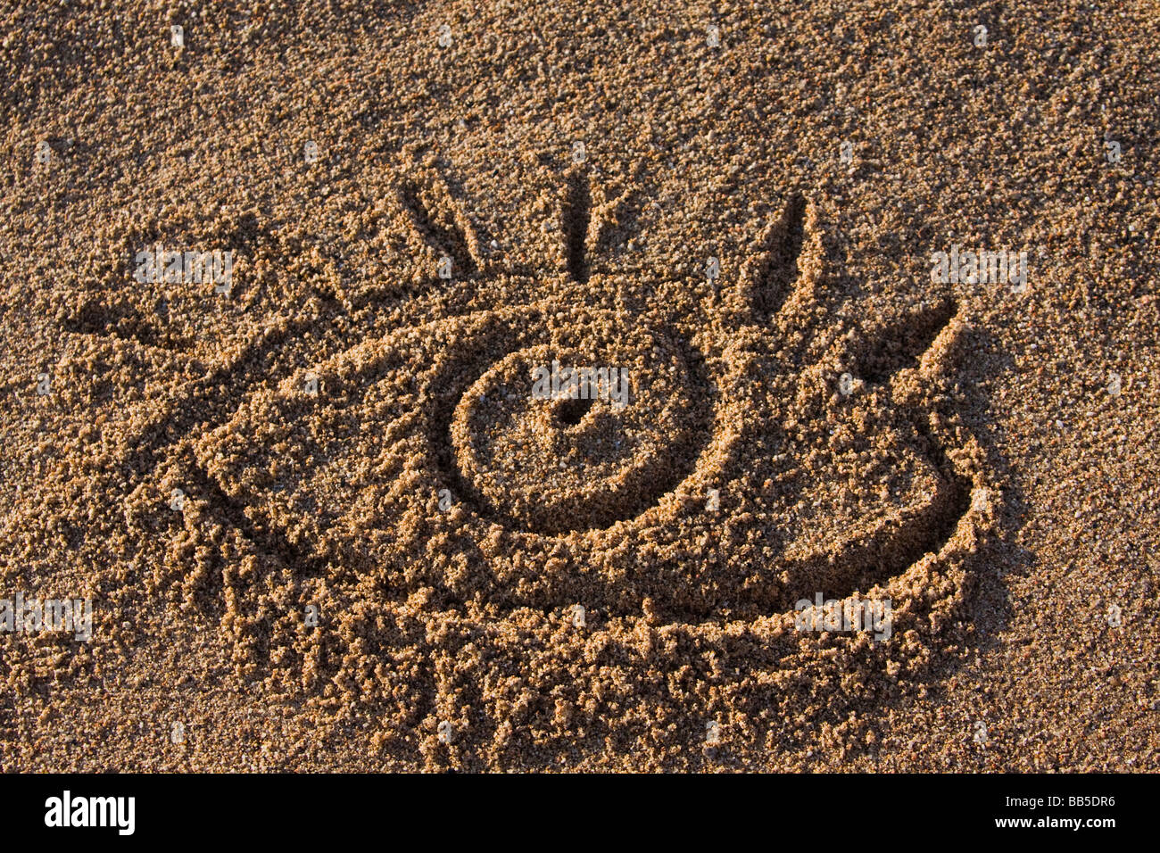 closeup of a eye sign in sand on a beach Stock Photo