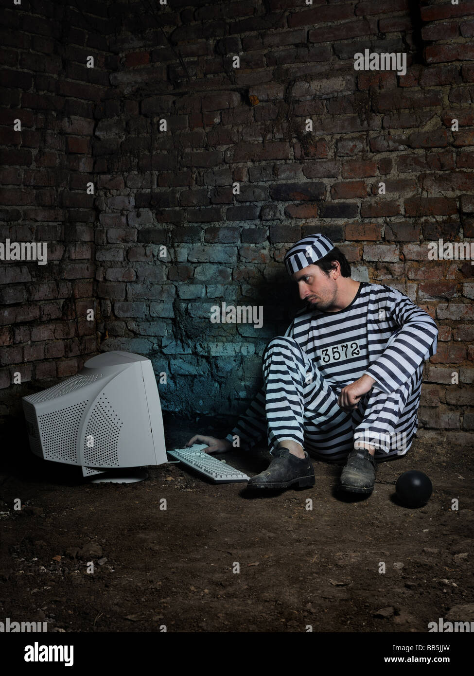 Prisoner in a dark cell working with computer Stock Photo Alamy