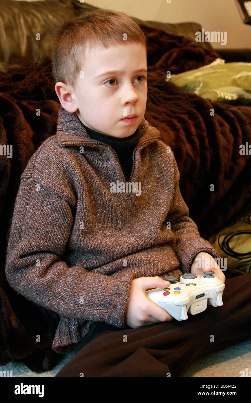 young boy playing holding remote controls for XBox 360. Stock Photo