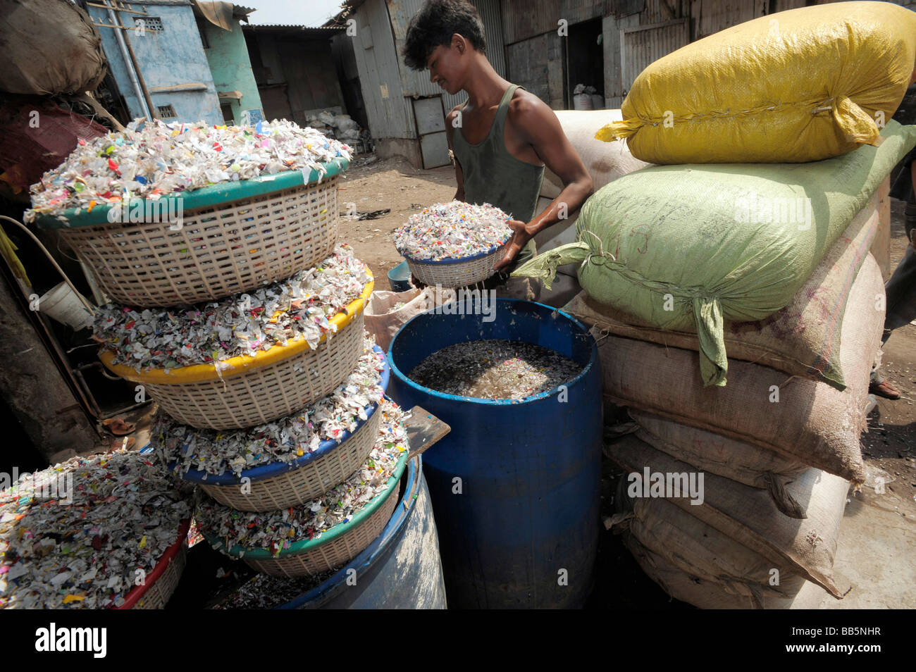 Baskets of plastic chips being washed by young Indian worker in Dharavi slums Stock Photo