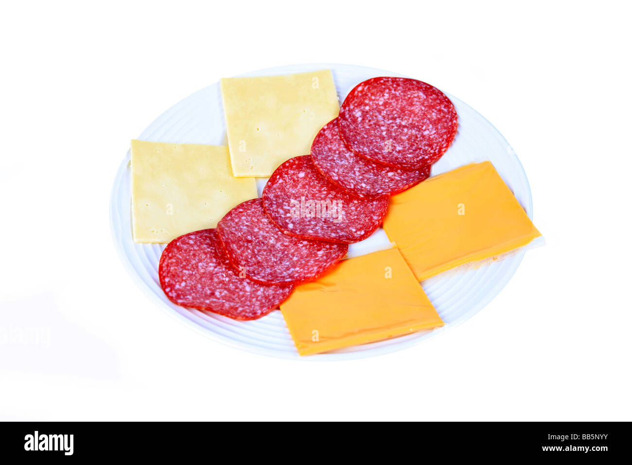 A lunchtime snack of slices of cheddar and processed cheese and German Salami sausage on a white