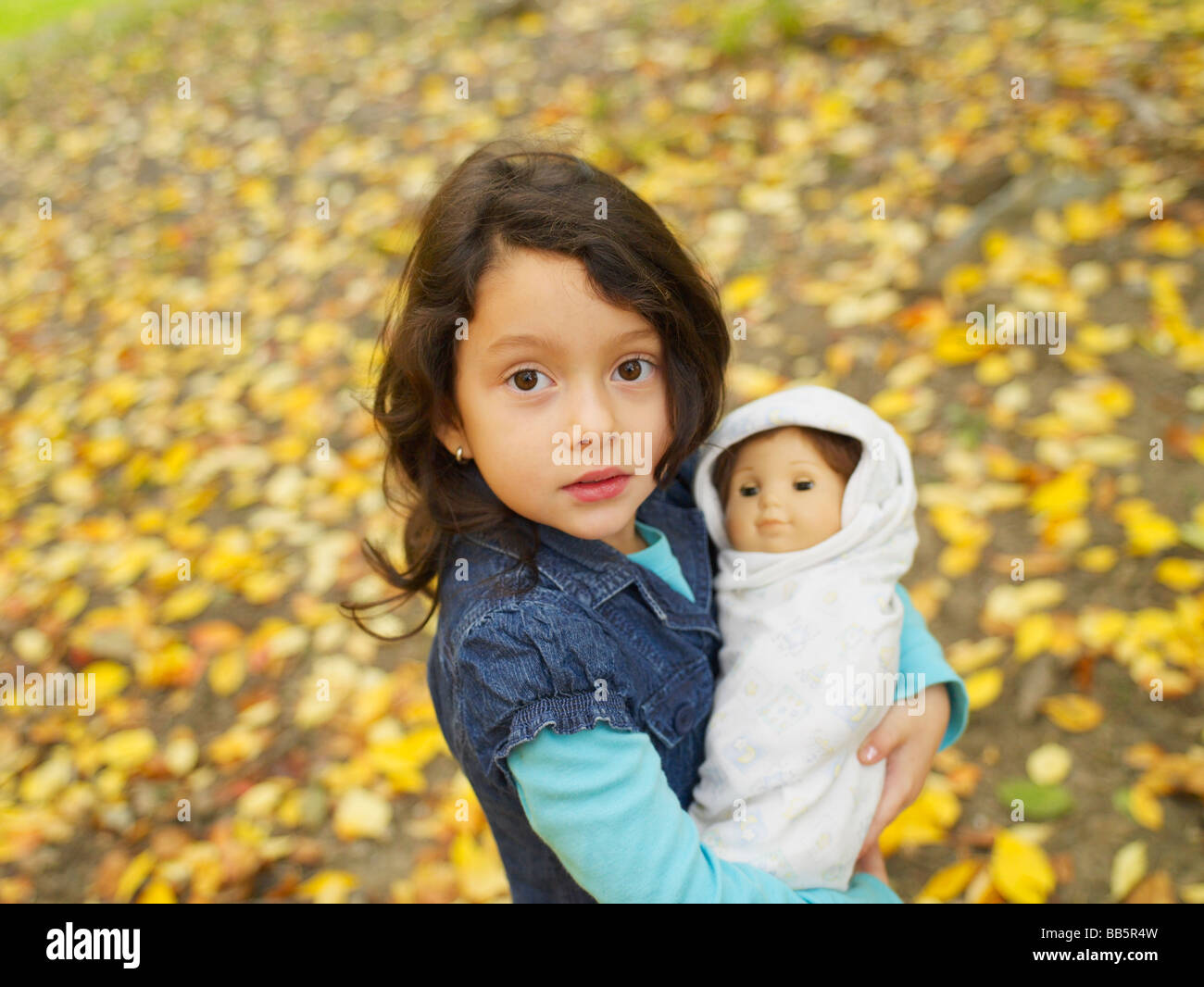 Hispanic girl playing outdoors with baby doll Stock Photo - Alamy