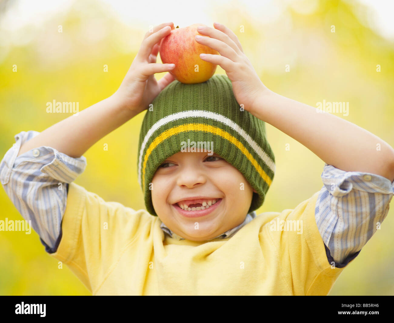 Toothless Hispanic boy balancing apple on head Stock Photo