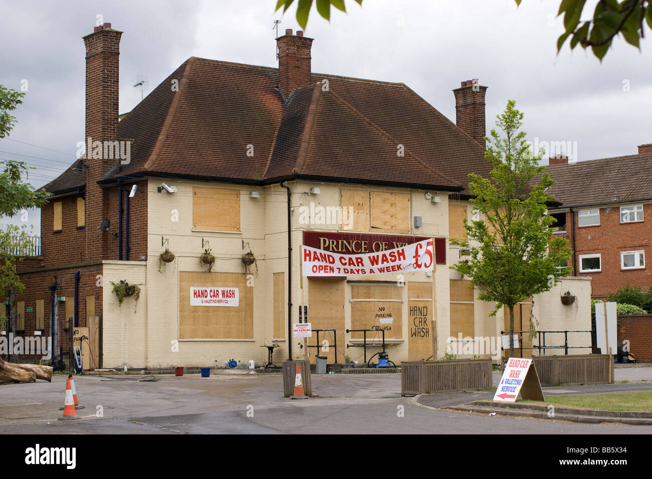 closed pub shut Prince of Wales public house with shuttered window and hand car wash signs in forecourt Chingford London Stock Photo