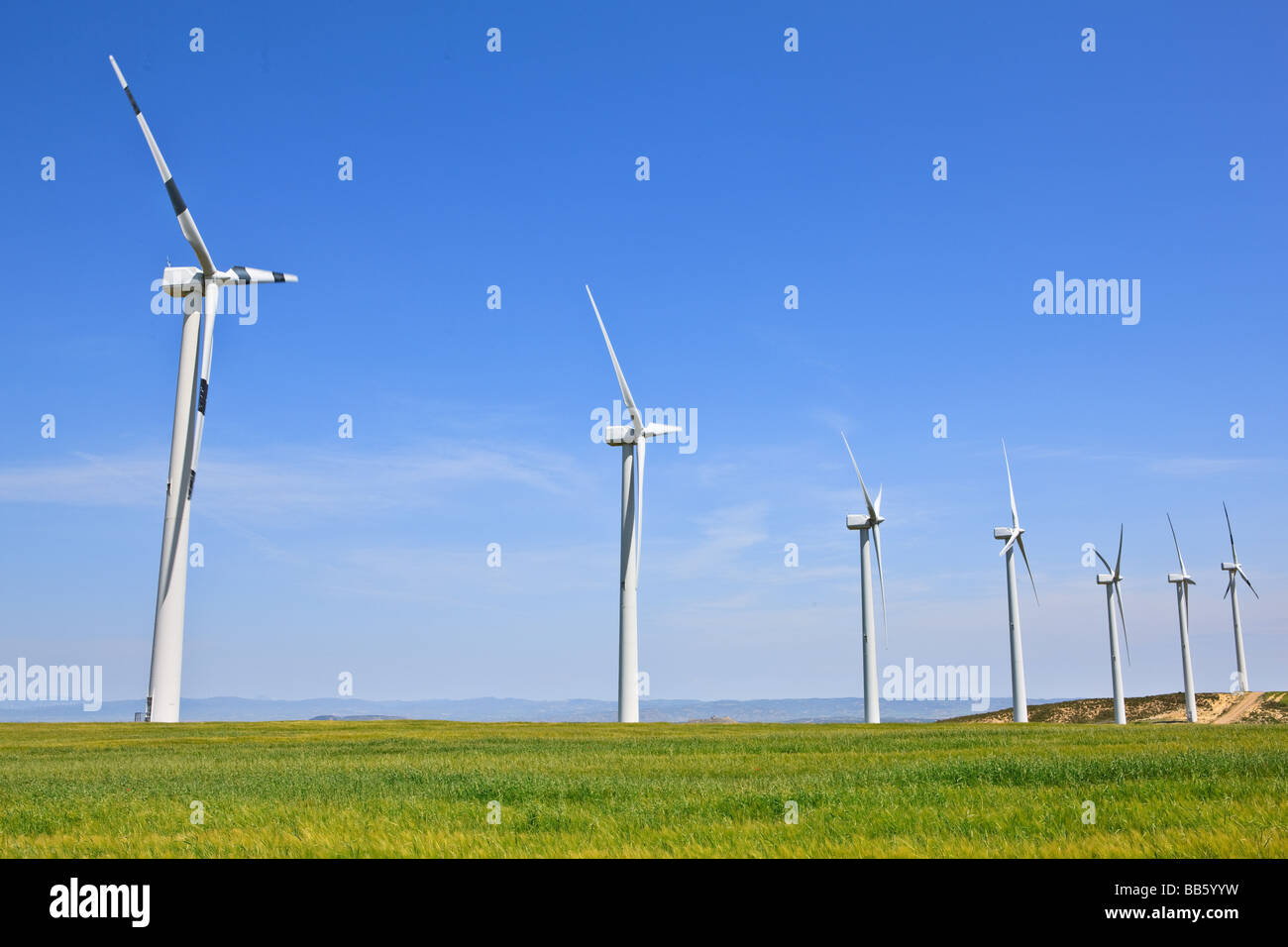 Wind turbines farm in green field over cloudy sky Stock Photo - Alamy