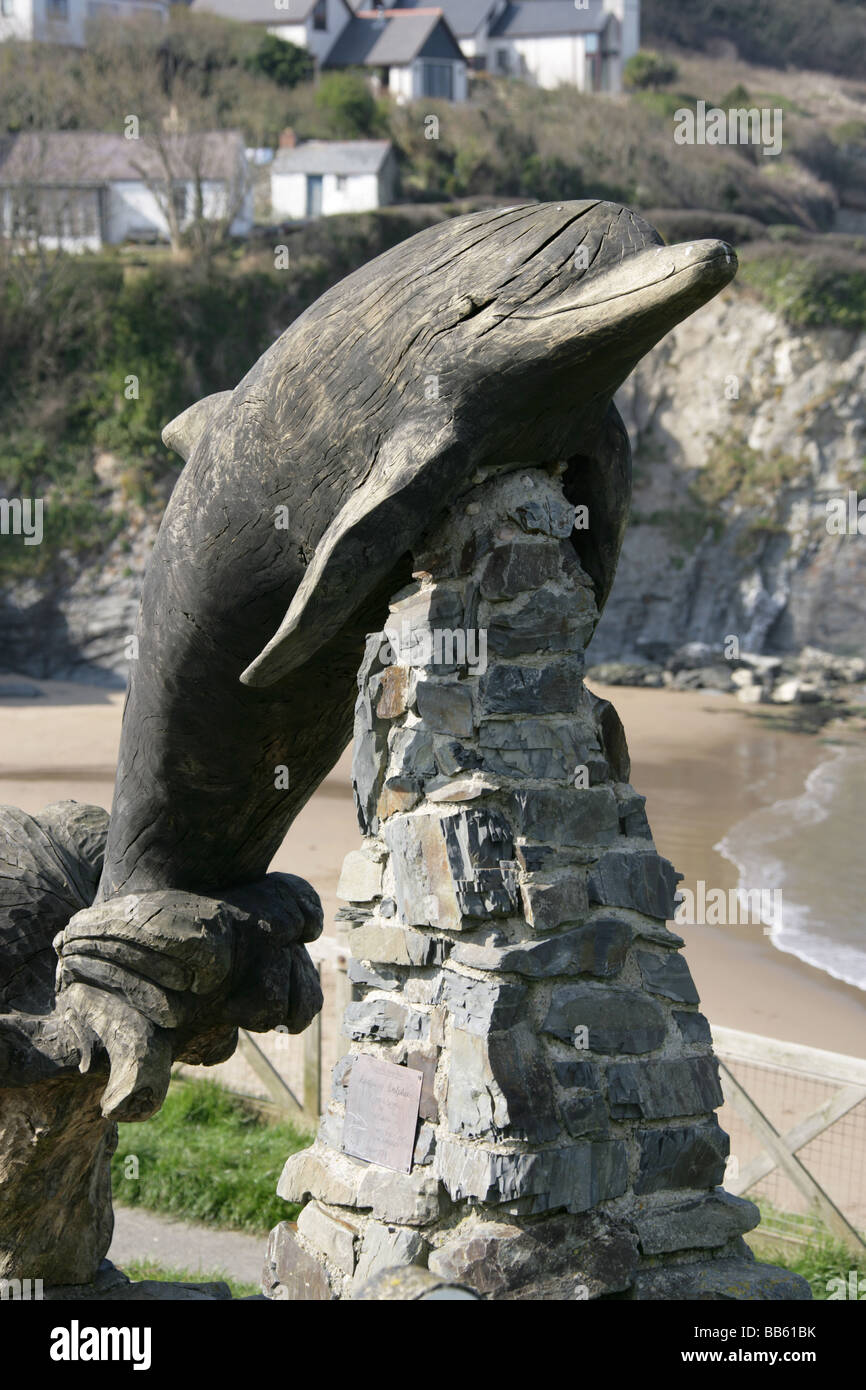 Village of Aberporth, Wales. The Paul Clarke designed Leaping Dolphin carving with Aberporth west beach in the background. Stock Photo