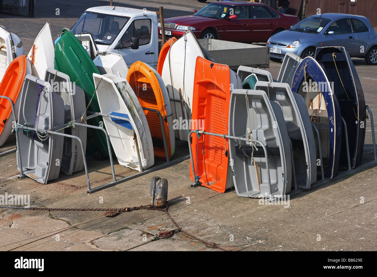 dingies and other small boats stored vertically to keep dry on the harbour side. Stock Photo
