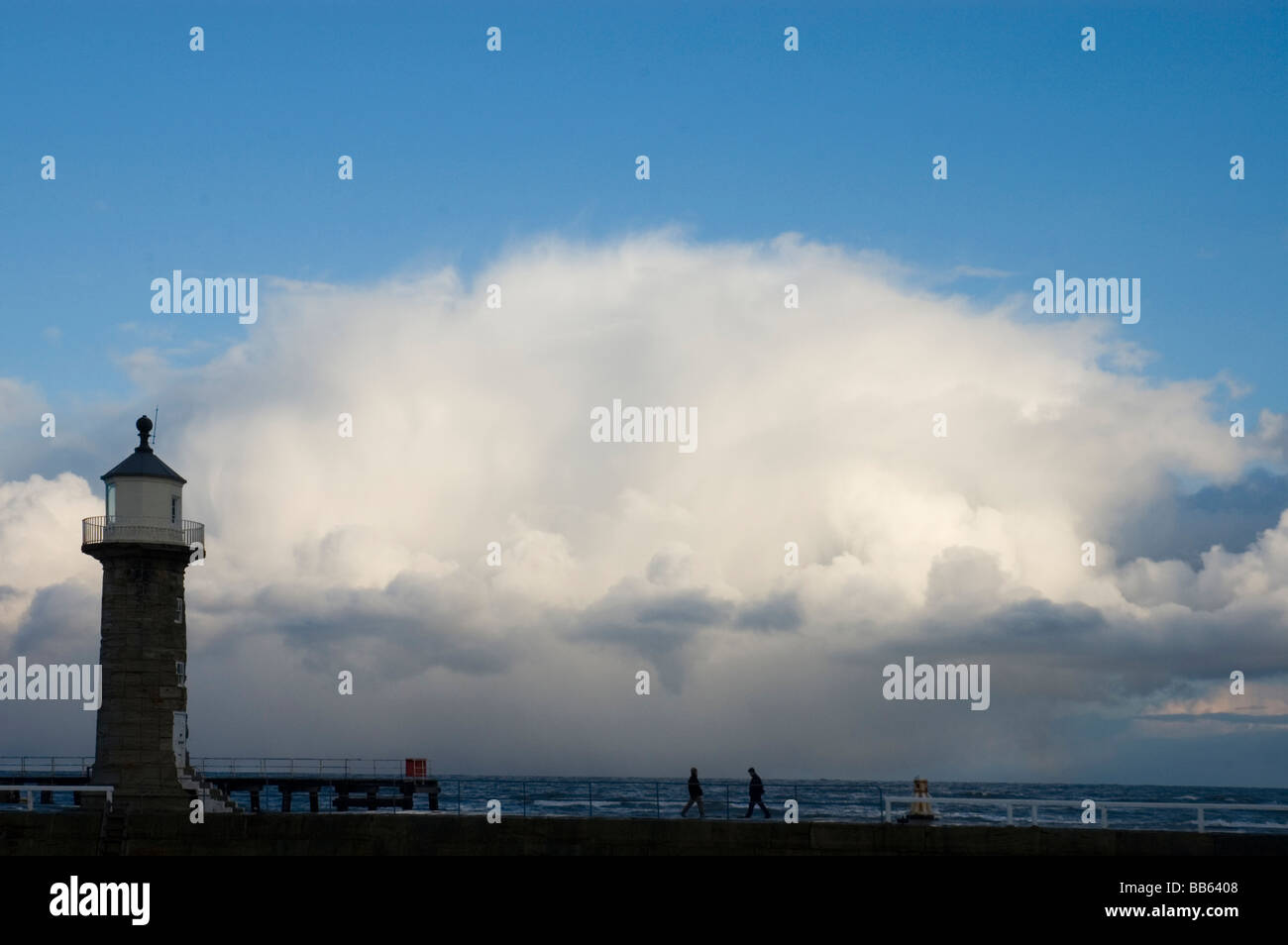 Winter storm approaches Whitby harbour with a lighthouse in the foreground Stock Photo