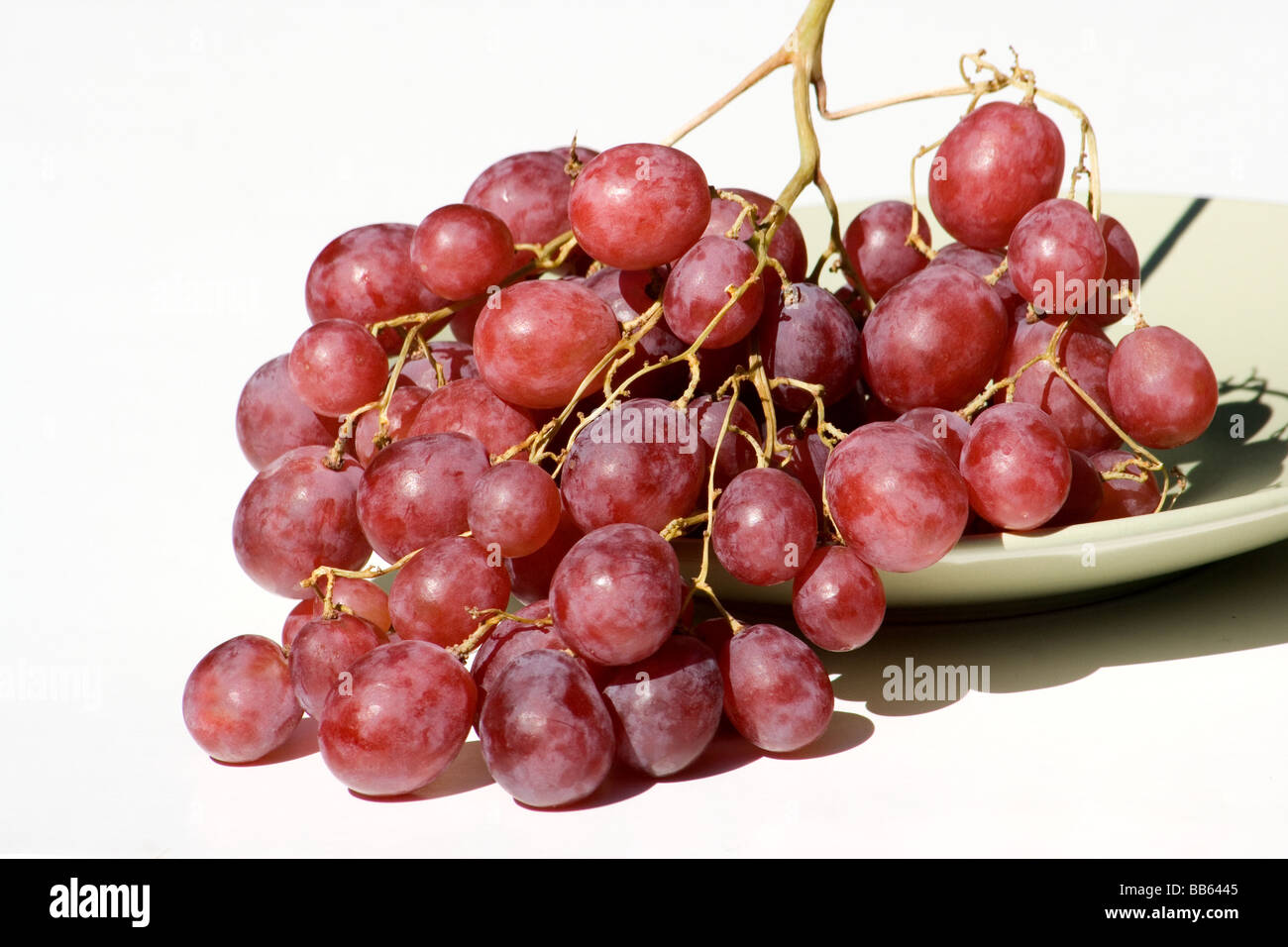 Cluster of red grapes in a plate on white background Stock Photo