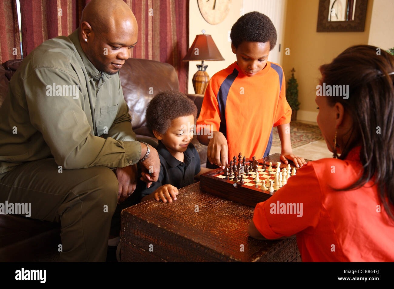 Family in living room playing chess together Stock Photo
