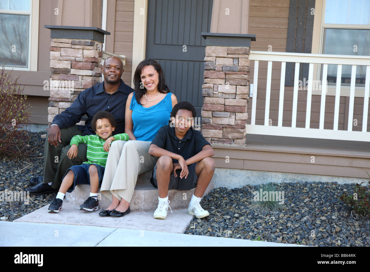 African American family sitting together on front steps of home Stock Photo
