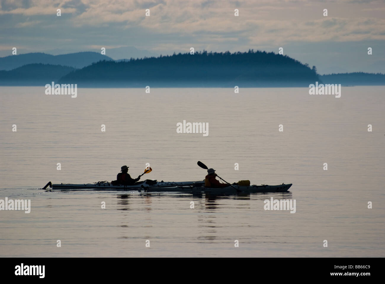 Two Kayaks at sunset make thier way past Lummi Island, Washington. Matia and Sucia Islands can