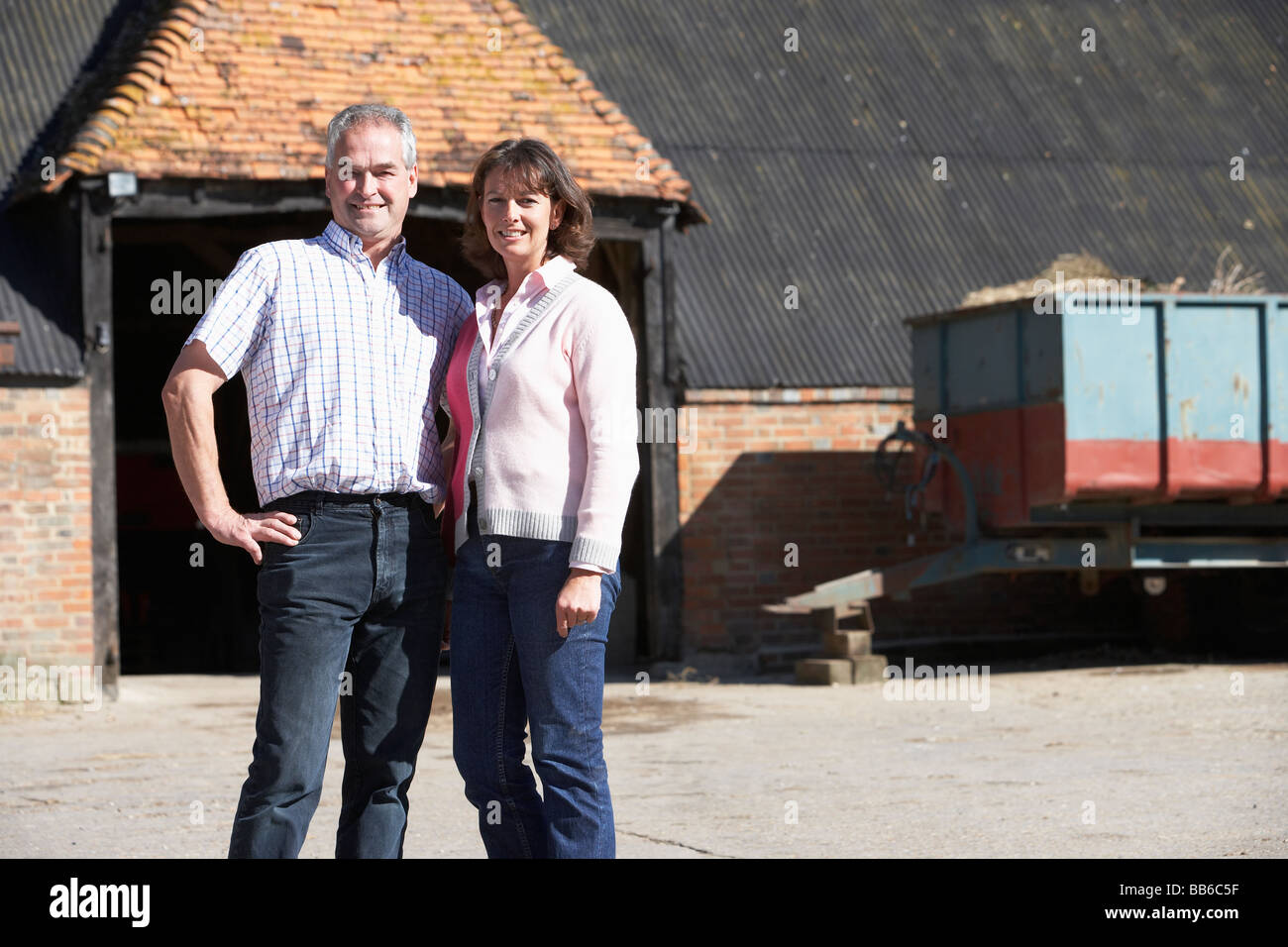 Farmer And Wife Standing In Front Of Farm Buildings Stock Photo - Alamy