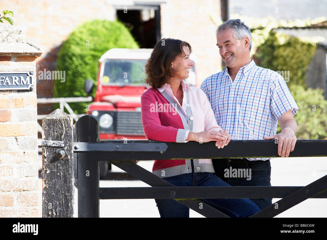Farmer And Wife Looking Over Farm Gate Stock Photo