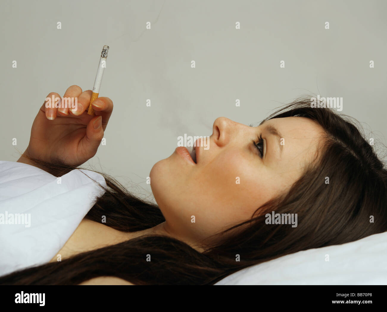 Young woman smoking in bed Stock Photo