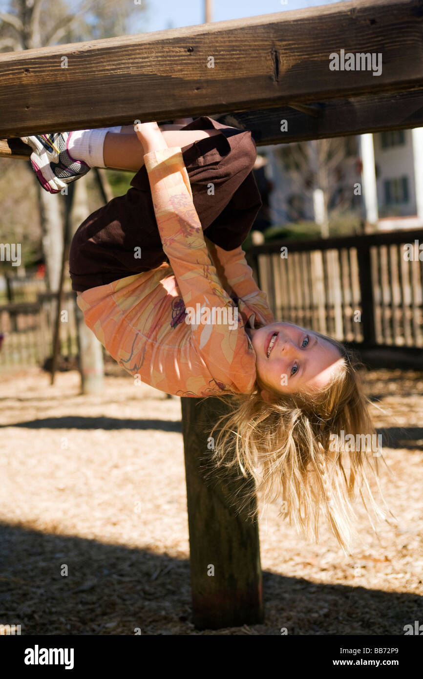 Young girl hanging upside down on monkey bars at playground - Franklin Park - Brevard, North Carolina Stock Photo