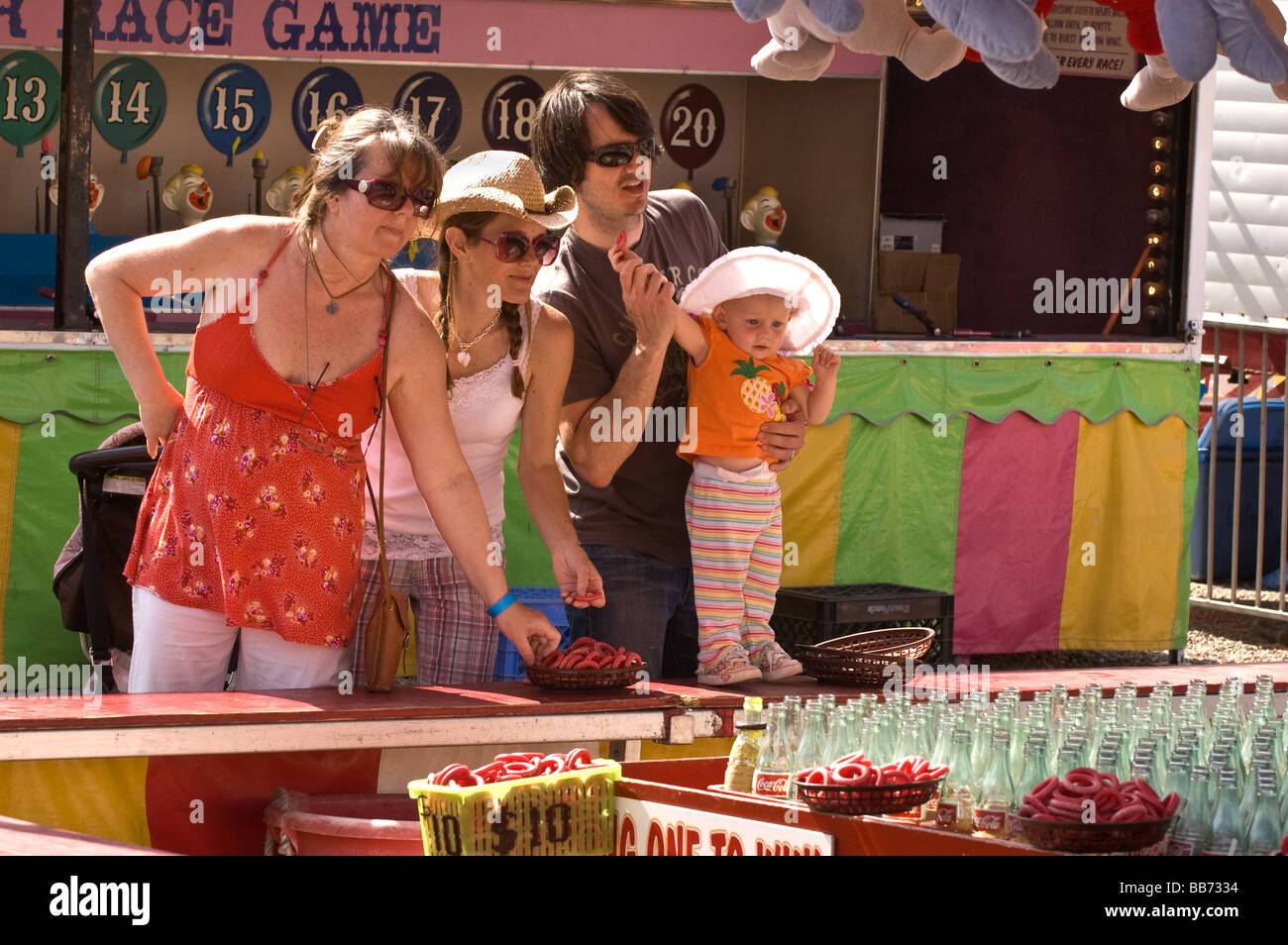A family at the "ring toss" booth helping a baby throw a ring Stock
