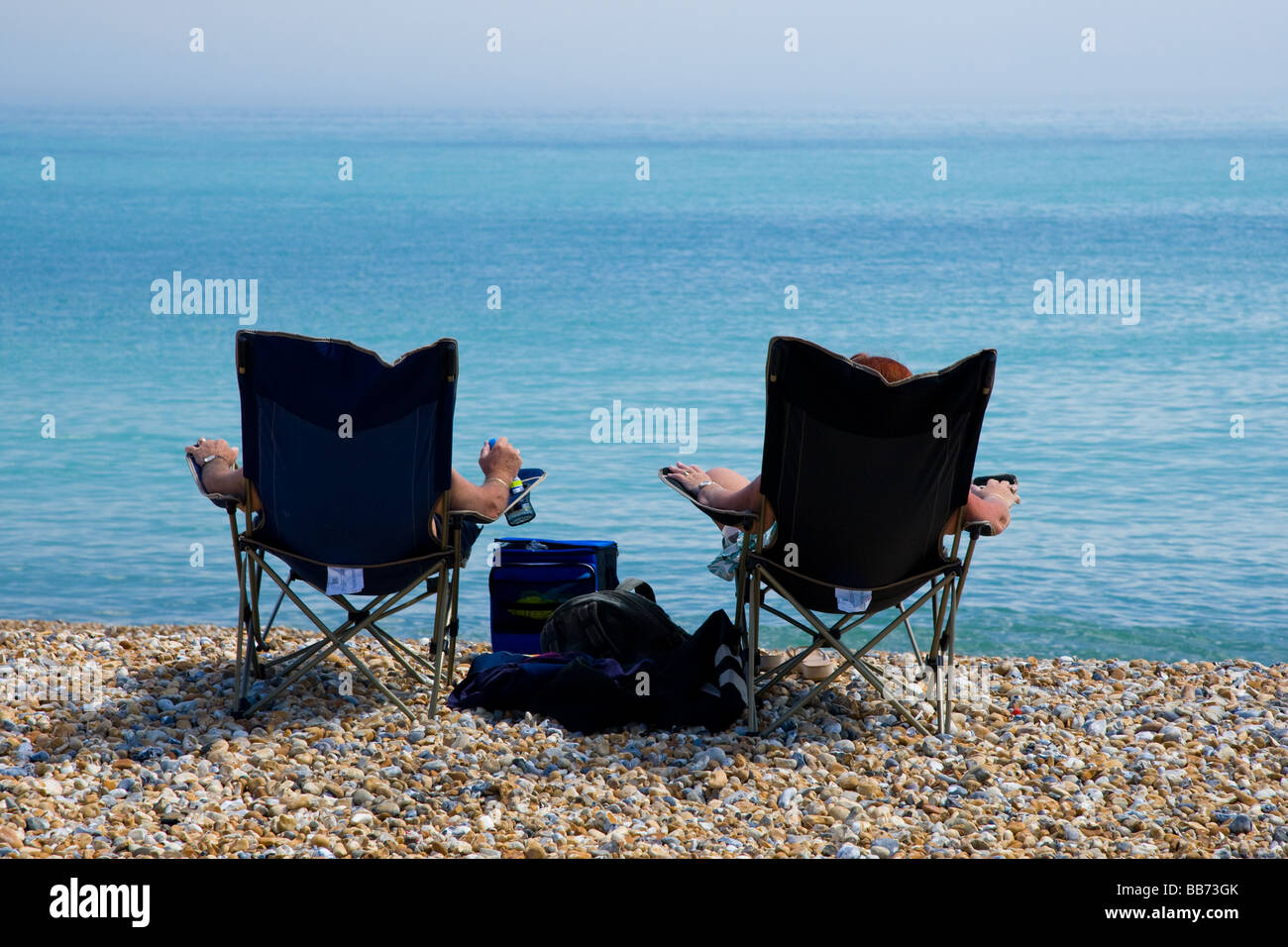 Two people soak up the sun on the beach Stock Photo Alamy